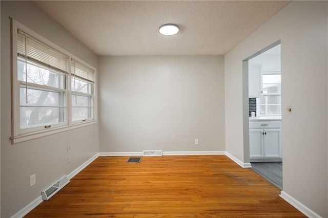 empty room featuring a textured ceiling and light hardwood / wood-style flooring