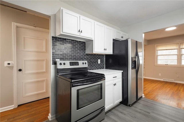 kitchen featuring white cabinetry, appliances with stainless steel finishes, backsplash, and light wood-type flooring