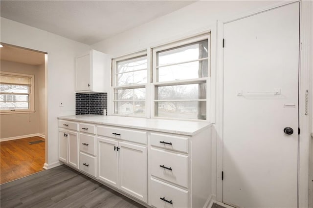 kitchen featuring white cabinetry, a healthy amount of sunlight, dark hardwood / wood-style floors, and backsplash