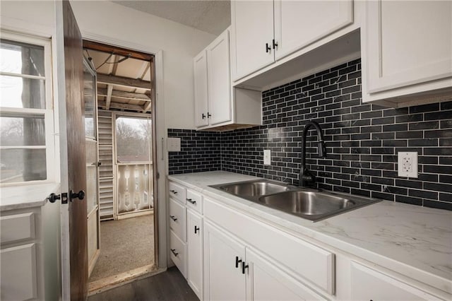 kitchen with sink, white cabinets, decorative backsplash, light stone countertops, and dark wood-type flooring