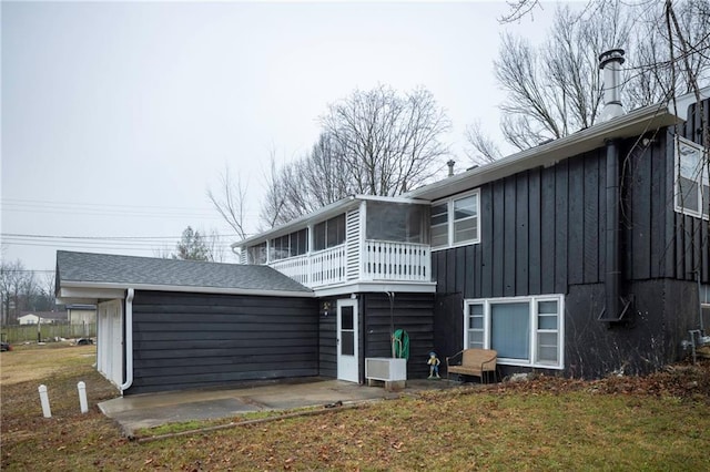 rear view of house featuring a sunroom, a patio, and a lawn