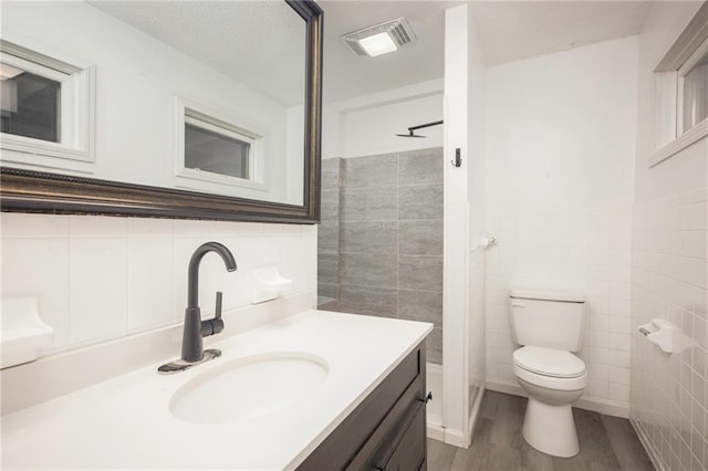 bathroom featuring tile walls, vanity, wood-type flooring, a textured ceiling, and toilet