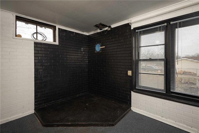 bathroom with plenty of natural light, ornamental molding, and brick wall