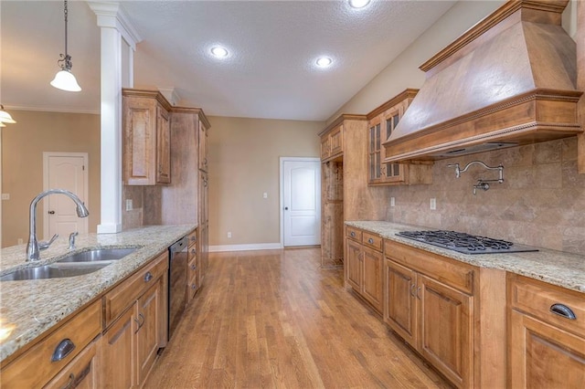 kitchen featuring light stone counters, decorative light fixtures, sink, and custom range hood