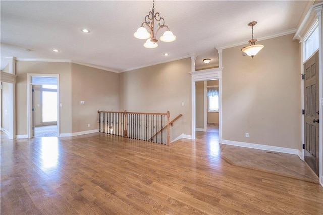 empty room featuring crown molding, a wealth of natural light, and light hardwood / wood-style floors