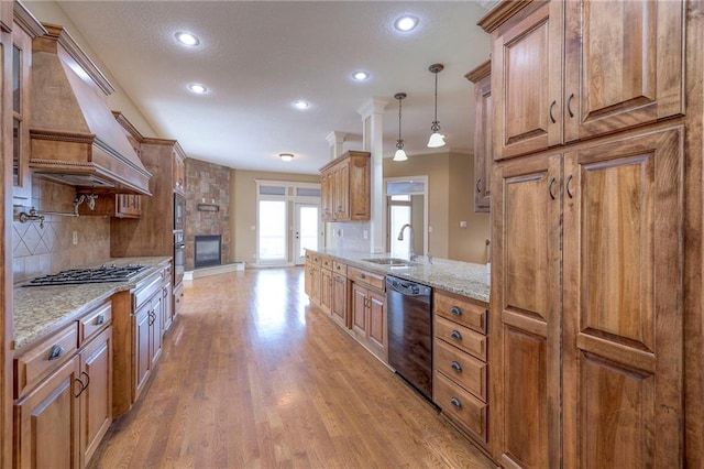 kitchen featuring pendant lighting, sink, light hardwood / wood-style flooring, premium range hood, and black appliances