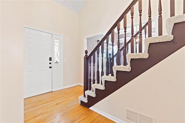 foyer featuring visible vents, stairway, baseboards, and wood finished floors