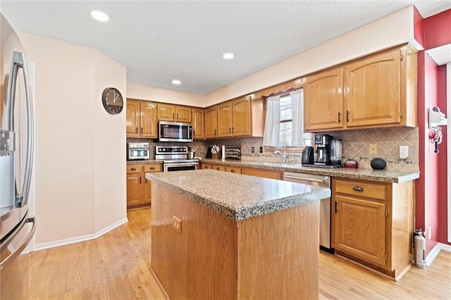 kitchen featuring stainless steel appliances, backsplash, light wood-type flooring, and a kitchen island