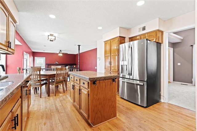 kitchen featuring brown cabinets, a kitchen island, visible vents, and stainless steel appliances