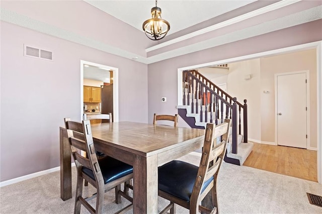 dining space featuring light colored carpet, visible vents, baseboards, stairs, and an inviting chandelier