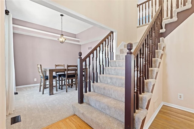 stairs featuring a tray ceiling, visible vents, baseboards, and wood finished floors