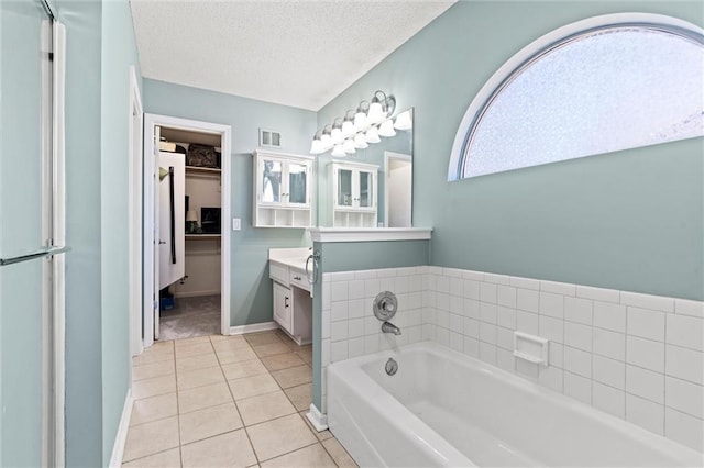 bathroom featuring a textured ceiling, a garden tub, tile patterned flooring, vanity, and visible vents