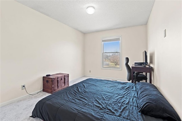 carpeted bedroom featuring a textured ceiling and baseboards