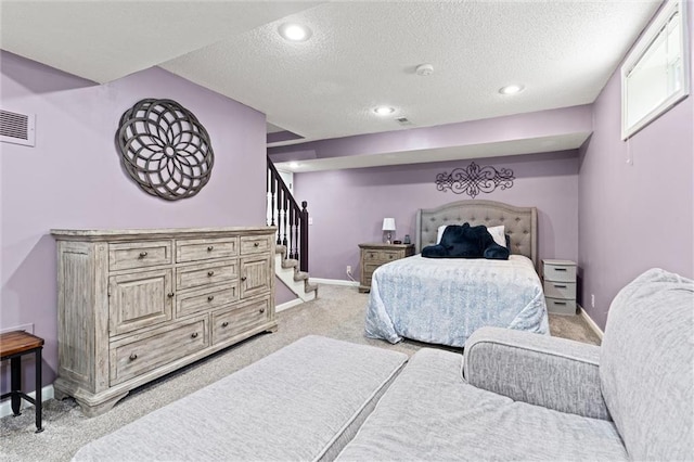 bedroom with light carpet, a textured ceiling, visible vents, and baseboards