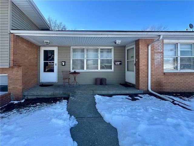 snow covered property entrance with covered porch