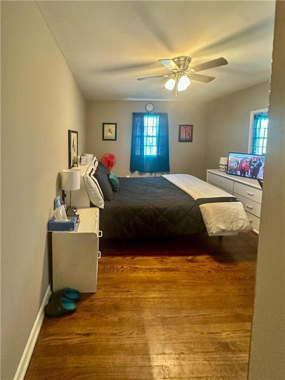 bedroom with multiple windows, ceiling fan, and dark hardwood / wood-style floors