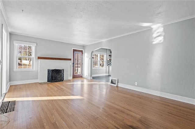 unfurnished living room featuring a fireplace, ornamental molding, and light wood-type flooring