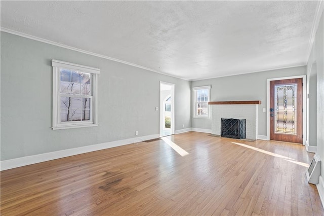 unfurnished living room with a brick fireplace, crown molding, and light hardwood / wood-style flooring