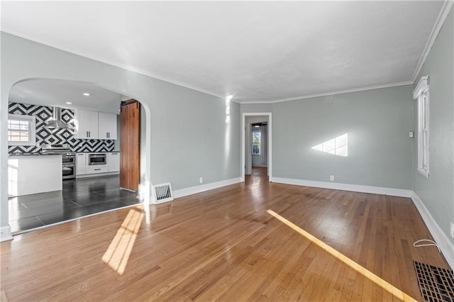 unfurnished living room featuring wood-type flooring and ornamental molding