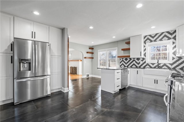 kitchen with kitchen peninsula, appliances with stainless steel finishes, backsplash, sink, and white cabinetry