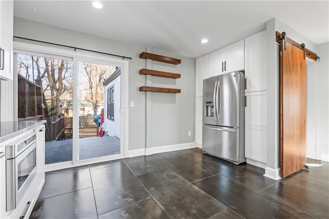 kitchen featuring white cabinets, a barn door, light stone countertops, and stainless steel appliances