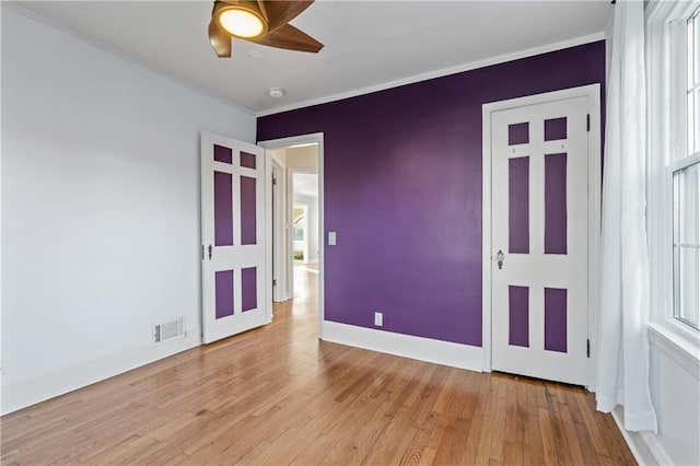 unfurnished bedroom featuring multiple windows, ceiling fan, light hardwood / wood-style floors, and ornamental molding