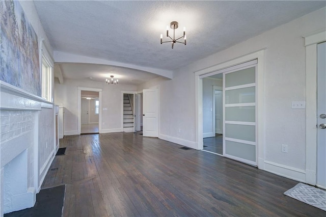 interior space with a chandelier, a textured ceiling, and dark wood-type flooring