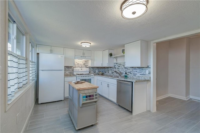 kitchen with butcher block counters, white cabinetry, tasteful backsplash, white appliances, and a kitchen island