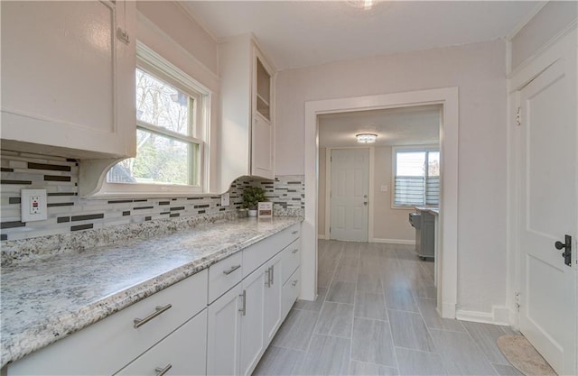 kitchen featuring decorative backsplash, white cabinetry, and plenty of natural light