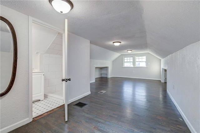 bonus room featuring a textured ceiling, vaulted ceiling, and dark hardwood / wood-style floors