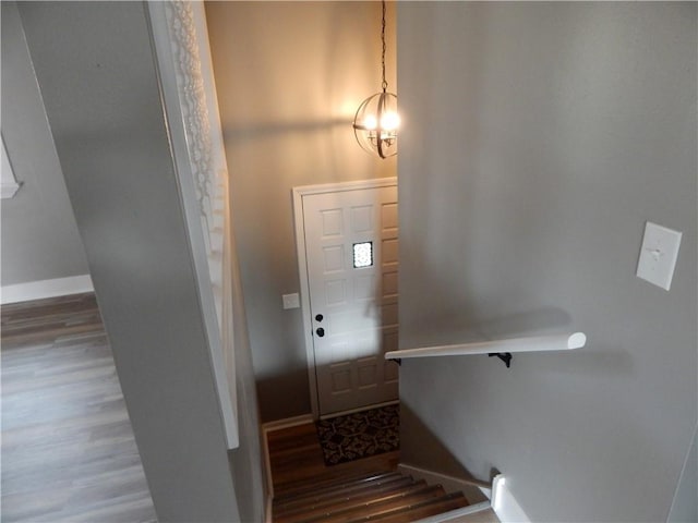 stairway with hardwood / wood-style floors and a notable chandelier