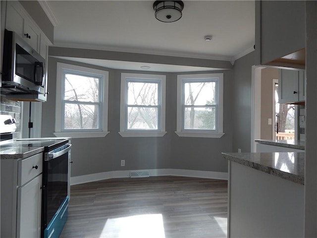 kitchen featuring electric range, white cabinets, light wood-type flooring, and a wealth of natural light