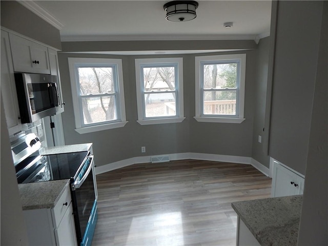 kitchen with a healthy amount of sunlight, white cabinetry, crown molding, and appliances with stainless steel finishes