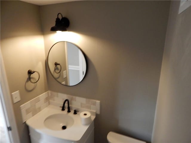 bathroom featuring tasteful backsplash, toilet, and sink