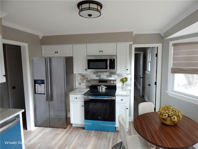 kitchen with tasteful backsplash, white cabinetry, stainless steel appliances, and light wood-type flooring