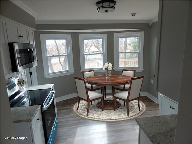 dining space featuring hardwood / wood-style floors, a healthy amount of sunlight, lofted ceiling, and ornamental molding