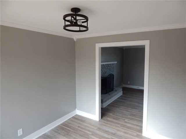 interior space featuring light wood-type flooring, a brick fireplace, and ornamental molding