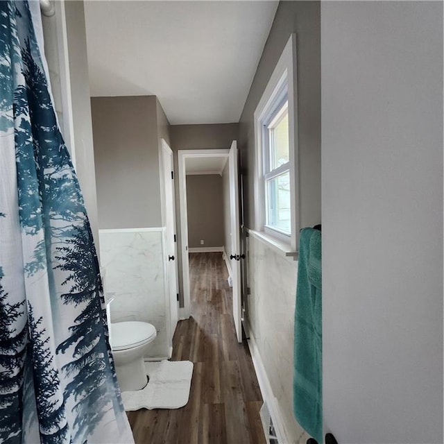 bathroom featuring hardwood / wood-style floors, toilet, and tile walls