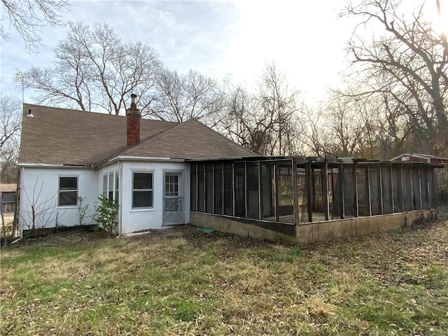 rear view of house with a lawn and a sunroom