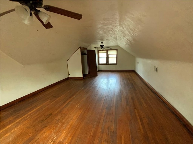 additional living space featuring dark hardwood / wood-style flooring, vaulted ceiling, and ceiling fan