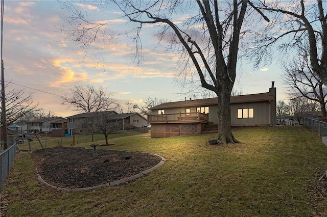 yard at dusk featuring a fenced backyard and a deck