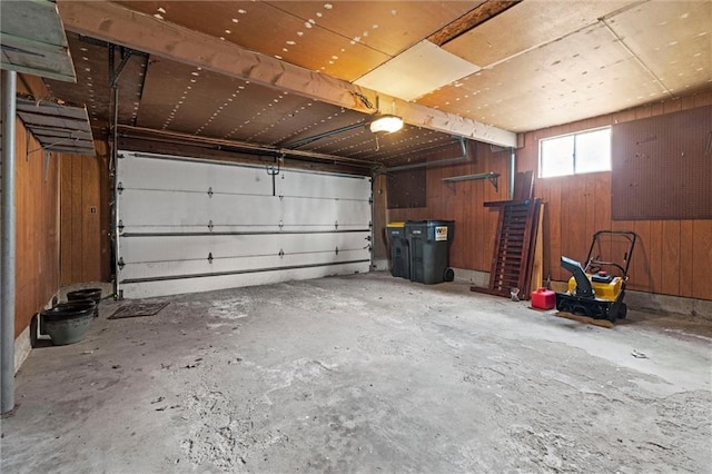 garage featuring a garage door opener and wooden walls