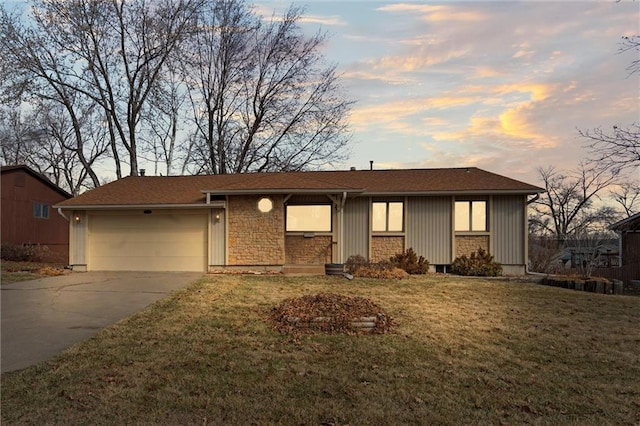 ranch-style home featuring a front lawn, concrete driveway, stone siding, and an attached garage