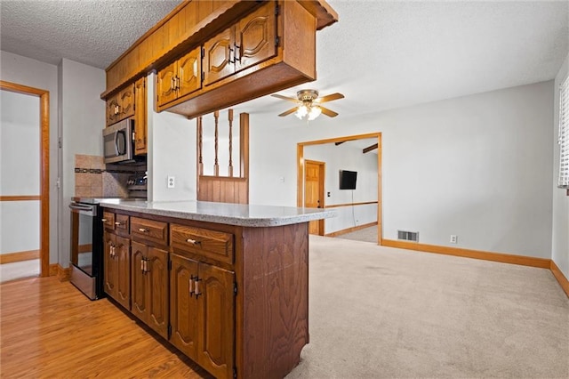 kitchen with baseboards, visible vents, appliances with stainless steel finishes, a peninsula, and a textured ceiling