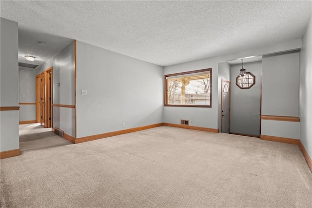 carpeted empty room with visible vents, baseboards, and a textured ceiling