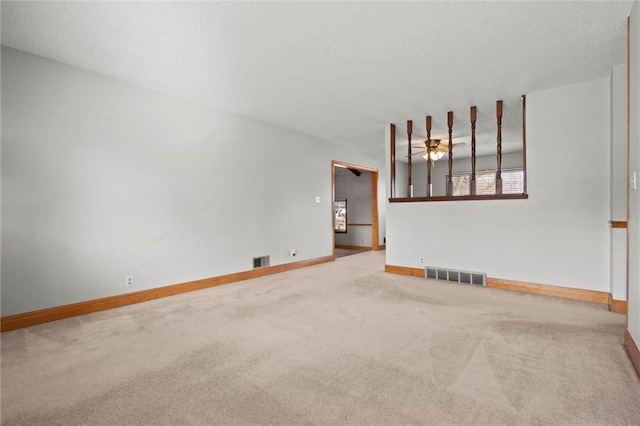 carpeted spare room with visible vents, ceiling fan, a textured ceiling, and baseboards