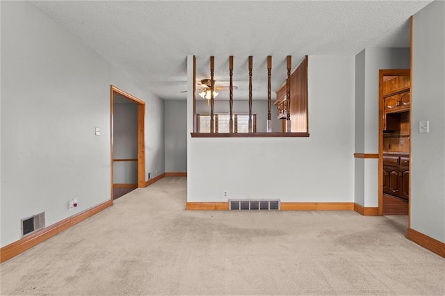 empty room featuring a textured ceiling, carpet flooring, visible vents, and baseboards