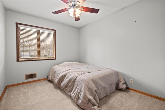 bedroom with light carpet, ceiling fan, visible vents, and baseboards