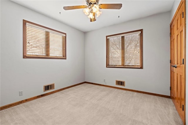 spare room featuring visible vents, ceiling fan, light carpet, and baseboards