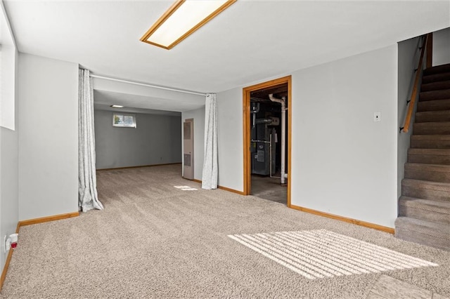 carpeted empty room featuring stairway and baseboards